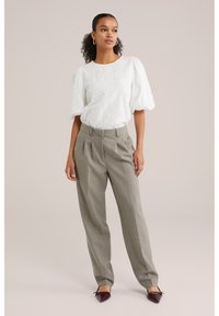 Valge tekstuuriga pluus pufsääristega, kombineeritud helehallide kortsuliste pükstega ja teravate burgundi värvi kingadega. Lihtne disain ilma mustriteta.