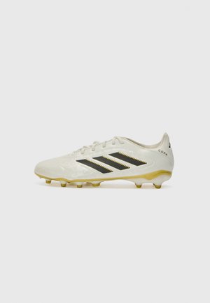 Witte voetbalschoen met zwarte strepen, gouden accenten en een gestructureerde oppervlakte. Beschikt over een snug ontwerp en conische noppen voor stabiliteit.