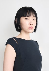 Dark navy dress with short sleeves and subtle cutouts at the shoulders. Smooth fabric, fitted design enhances the silhouette.