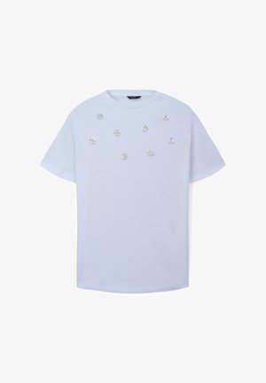 T-shirt in cotone azzurro chiaro con maniche corte, decorato con embellishments a forma di fiore sparsi sulla parte anteriore. Collo rotondo.