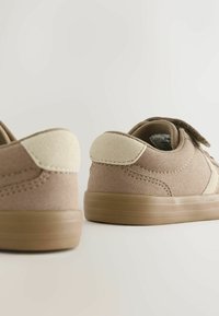 Brune ruskind sko med en tekstureret overflade, beige detaljer på hælen og en gummisål. Velcro-rem for sikker pasform.