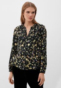 Schwarze Bluse mit Blumenmuster, mit durchgehender Knopfleiste, langen Ärmel und lockerer Passform. Der Stoff hat eine weiche Textur mit mehrfarbigen Blumenmustern.
