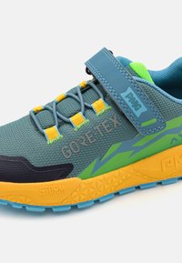 Chaussure de course légère avec une tige texturée bleu-vert, des accents jaunes, un logo GORE-TEX et une semelle extérieure en caoutchouc pour l'adhérence.