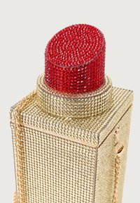 Χρυσή μεταλλική τσάντα με διακοσμητικά από ρινοστάτες, με κόκκινη ρινοστάτη κορυφή και χρυσή αλυσίδα. Τετράγωνο σχήμα με γυαλιστερή επιφάνεια.