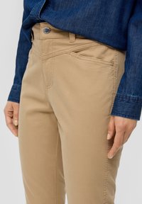 Beiga bomullsblandade byxor med slim fit, med en framficka, sömnadsdetaljer och en metallknapp vid midjan.