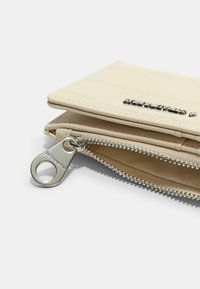 Crocodile-textured cream wallet with a silver zipper and keychain loop. Features a smooth finish and compact design, ideal for storage.
