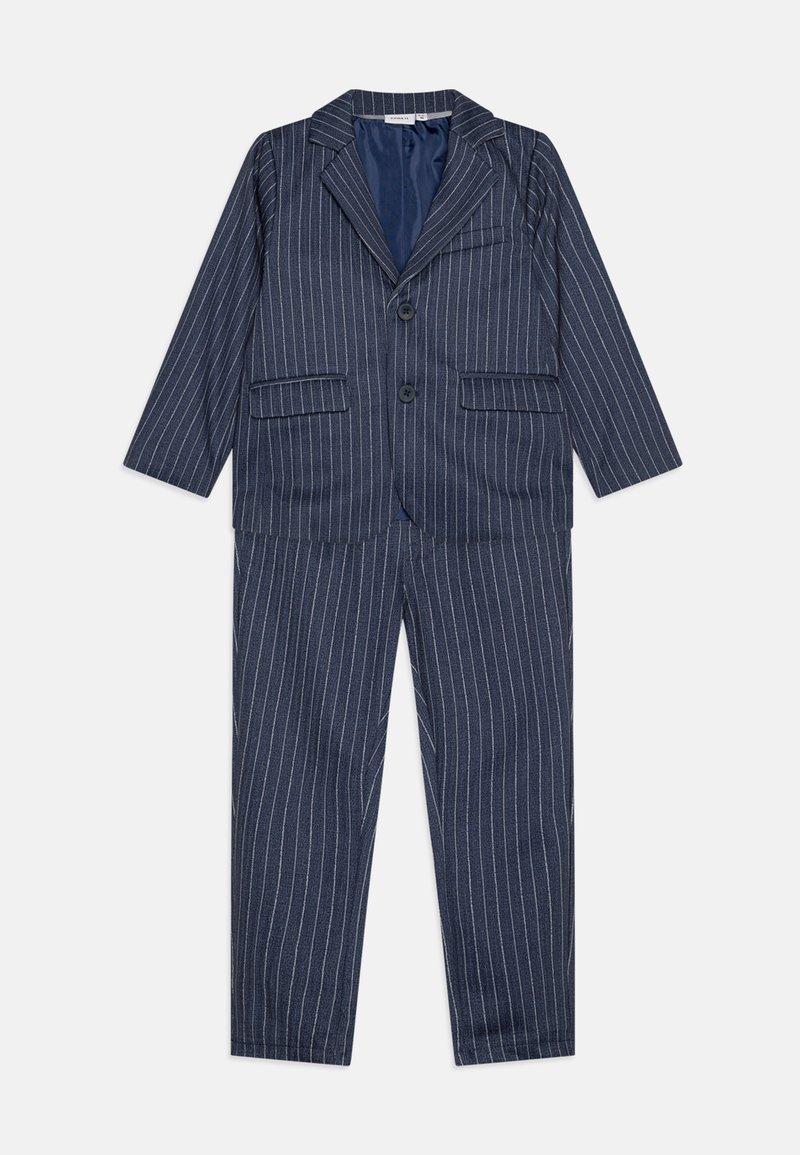 Tumesinine pinstripes ülikond, mis sisaldab bleiserit kahe esipocketiga ja ühe nööbiga kinnitusega, sobituvad sirged püksid.