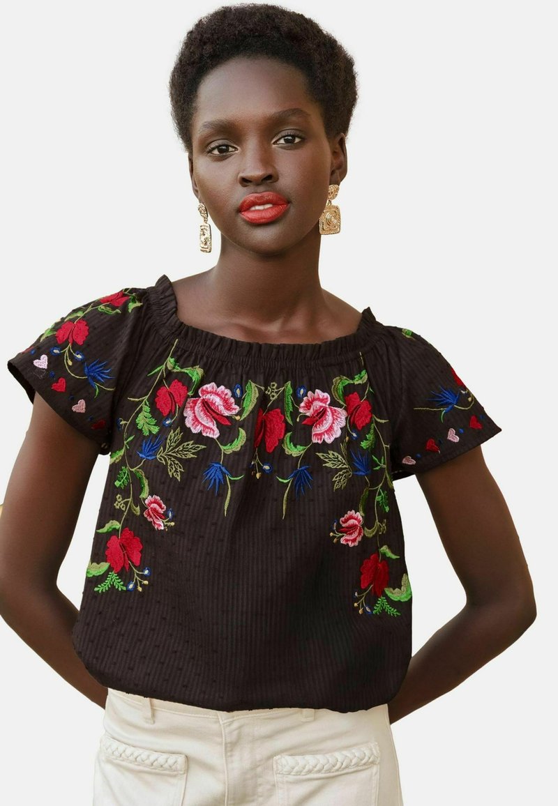 Black embroidered blouse featuring floral patterns in red, pink, green, and blue, with short sleeves and a gathered neck design.