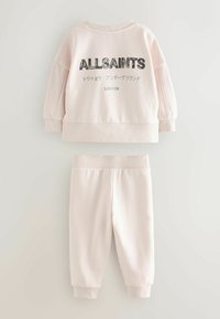 Beige tvådelad outfit för småbarn med långärmad sweatshirt som har "ALLSAINTS" och japansk text, tillsammans med matchande byxor med uppvikta ben.