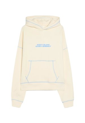Crèmekleurige hooded sweater met frontzak, blauwe stiksels en lichtblauwe tekst "SOFT GLOW QUIET ENERGY" op de borst.
