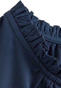 Tessuto blu navy con bordo arricciato, caratterizzato da dettagli testurizzati. Il tessuto appare morbido con una leggera lucentezza e una cucitura elastica arricciata.