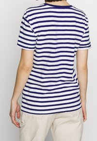 Camiseta de algodón con rayas horizontales en azul marino y blanco, de manga corta, corte relajado, cuello redondo y detalle de costura visible en el dobladillo.
