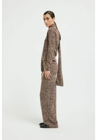 Strickset in lila- und brauntönen, mit hohem Kragen, langen Ärmeln und seitlichen Bändern, in lockerem Schnitt und mit glatter Textur.