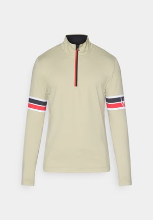 Długi rękaw pulower w jasnym khaki, z kołnierzem na ćwierć zamka, czarnymi i czerwonymi akcentami na ramionach oraz paskowanym wzorem na rękawach.