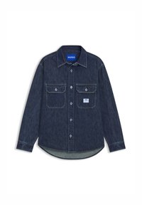 Camisa de mezclilla azul oscuro con dos bolsillos frontales, cierre de botones, mangas largas y dobladillo redondeado. Presenta una etiqueta de marca en color contrastante.