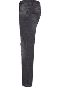 Jeans skinny negros con un acabado desgastado, que presentan detalles desgastados en la parte frontal y un diseño de cinco bolsillos; hechos de tela de mezclilla.