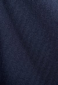 Granatowy, teksturowany materiał o drobnej fakturze, zbliżenie na jego gładką powierzchnię i wielokierunkowe włókna.