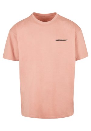 Jasnoróżowy T-shirt z krótkim rękawem i okrągłym dekoltem, z małym czarnym napisem "MJGONZALES™" na lewej piersi.
