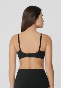 Bralette noire avec bretelles ajustables, en matériau stretch lisse, design minimaliste et dos sans coutures.
