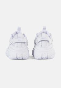 Zapatillas deportivas blancas con paneles de malla, cuello acolchado y suela de goma con un patrón de pisada texturizado. Marca en el talón.