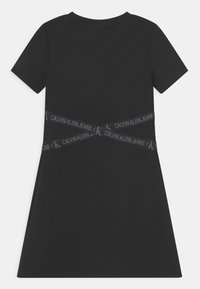 Czarna bawełniana sukienka T-shirt z krótkimi rękawami, rozszerzanym krojem oraz teksturowanym paskiem z logo "CALVIN KLEIN JEANS" na wysokości talii.