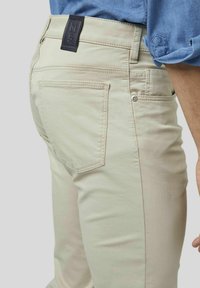 Beige katoenen broeken hebben een slim fit, achterzakken met gestikte details en een gelabelde zwartleren tailleband.