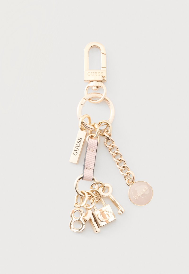 Porte-clés Guess ton or avec un fermoir homard, maillon de chaîne, breloques incluant les chiffres 8 et 1, un cadenas, une clé et des étiquettes de marque.