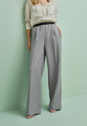 Gray wide-leg trousers with a textured finish and black elastic waistband, paired with a light beige button-up shirt.