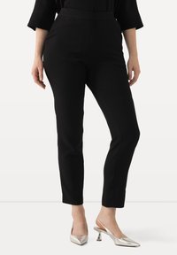 Zwarte op maat gemaakte broek met een slim fit, hoge taille en een gladde textuur. Gecombineerd met metallic zilveren puntige hakken.