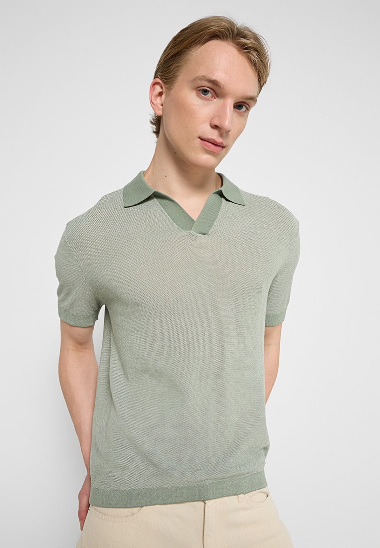 Hellgrünes, kurzärmeliges Poloshirt mit V-Ausschnitt, strukturiertem Strickstoff und kontrastierendem Kragen. Schlichtes, modernes Design.