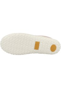 Semelle de chaussure en caoutchouc blanc avec des motifs triangulaires texturés, arborant un patch logo jaune et un accent circulaire marron près du talon.