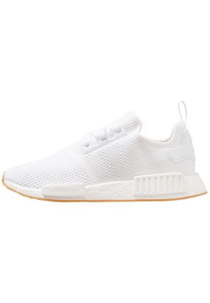 Valkoinen Adidas NMD -lenkkari, jossa neulottu päällinen, kolme raitaa sivulla, nauhakiinnitys ja kumiulkopohja.