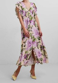 Robe maxi florale avec un décolleté en V et des manches volantées. Composée d'un tissu beige clair orné de fleurs roses et de feuilles vertes. Fentes sur les côtés.