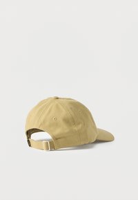 Μπεζ βαμβακερό καπέλο μπέιζμπολ με ρυθμιζόμενο λουράκι και μεταλλική πόρπη, εμφανιζόμενο σε λευκό φόντο, από πίσω όψη.