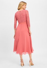 Rosa Kleid mit einem Oberteil aus glitzernder Spitze und langen Ärmeln, fließendem Chiffonrock, knöchellang, kombiniert mit Riemchen-High-Heels.