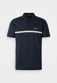 Πόλο μπλούζα σε ναυτικό μπλε χρώμα, κατασκευασμένη από υφασμάτινο υλικό με υφή, με δύο κουμπιά στη λαιμόκοψη και οριζόντια λευκή ρίγα στο στήθος με λεπτομέρεια λογοτύπου.