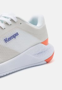 Kempa tenisice imaju gornji dio od svijetlo sivoj mrežastog materijala, bijeli gumeni potplat i narančasti detalj na peti. Šnure su bijele s teksturiranim uzorkom.