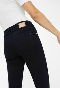 Diepblauwe jeans hebben een slim fit silhouet, een leren logo patch op de achterkant en subtiele details op de achterzakken.