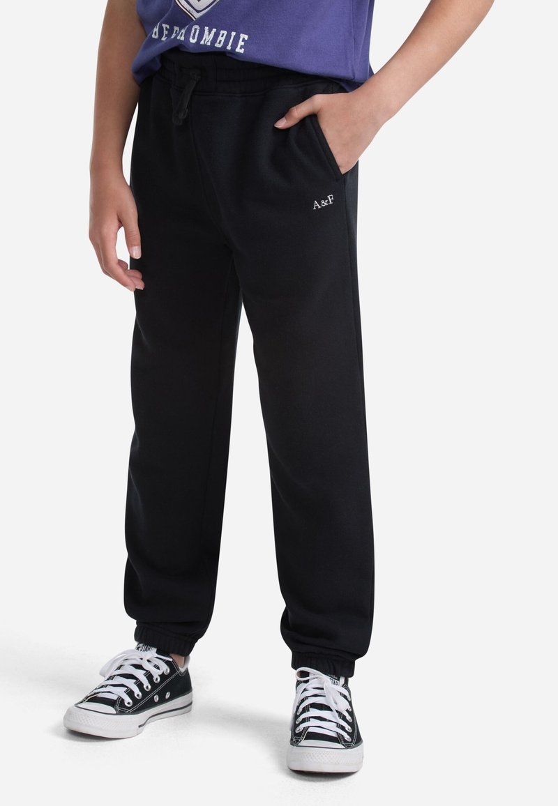 Pantalones de chándal negros de algodón con cintura elástica, bolsillos laterales y tobillos ajustados. Presenta un pequeño logo en el lado izquierdo.