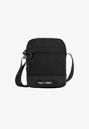 Sac bandoulière noir de forme rectangulaire, fabriqué en tissu durable. Il dispose d'une poche zippée à l'avant et d'une étiquette de marque en bas.