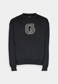Sweat-shirt noir à col rond avec manches longues et une grande lettre "G" grise texturée avec le texte "GAP" centré sur la poitrine.