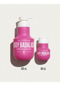 Dos botellas rosas de loción de agua refrescante para la piel Sol de Janeiro Body Badalada, una de 400 ml con bomba y otra de 100 ml con tapa abatible, sobre un fondo blanco.
