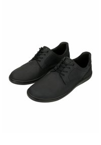 Scarpe di pelle nera con una finitura liscia, a profilo basso, design con lacci e cuciture discrete sui lati. Suola in gomma flessibile.