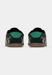 Μαύρα παπούτσια με πράσινες πινελιές, κεντήματα με λουλούδια και λευκές ρίγες. Υπόδημα με υφή στο πάνω μέρος και λαστιχένια σόλα με σχεδιασμό χαμηλού προφίλ.