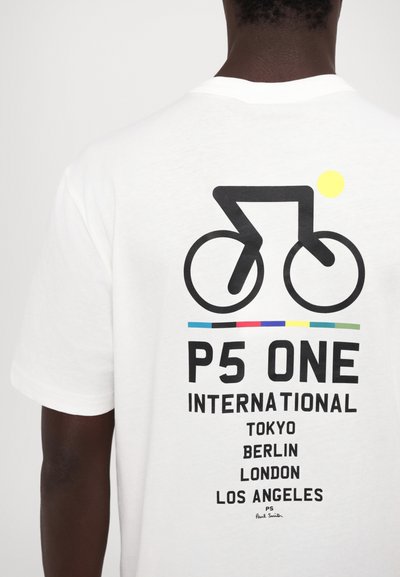 Camiseta blanca de algodón con un gráfico de bicicleta y rayas horizontales multicolores. El texto lista ciudades: Tokio, Berlín, Londres, Los Ángeles.