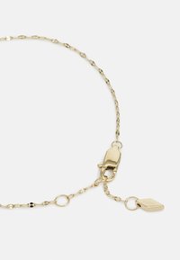 Collana a catena color oro con anelli ovali, chiusura a moschettone e un'etichetta con la scritta "FOSSIL" incisa. Texture liscia e finitura lucida.