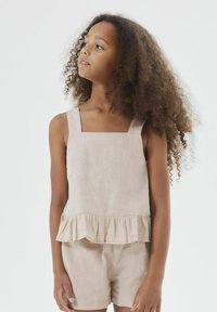 Top senza maniche in lino beige con scollatura quadrata e orlo a volant. Abbinato a pantaloni corti in lino beige coordinati. Tessuto morbido, design casual.