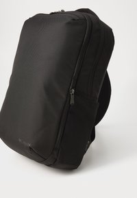 Zaino nero realizzato in tessuto texturizzato, dotato di due scomparti con zip, tasca laterale in rete e pannello posteriore imbottito per il comfort.