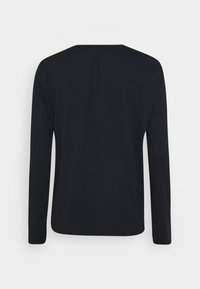 Schwarzes Langarmshirt von hinten gezeigt, mit einem kleinen zentralen Faltendetail unter dem Ausschnitt und einem schlichten Saum.