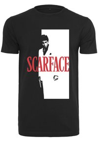 Svart t-skjorte med grafisk trykk av en person i hvit dress som holder en pistol, med "SCARFACE" i fet røde bokstaver.